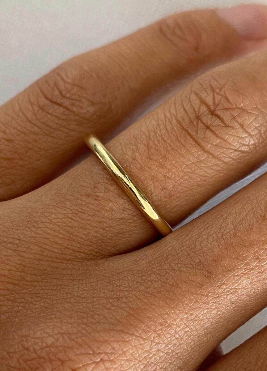 Wedding Ring Design: A plain gold metal band on a ring finger.