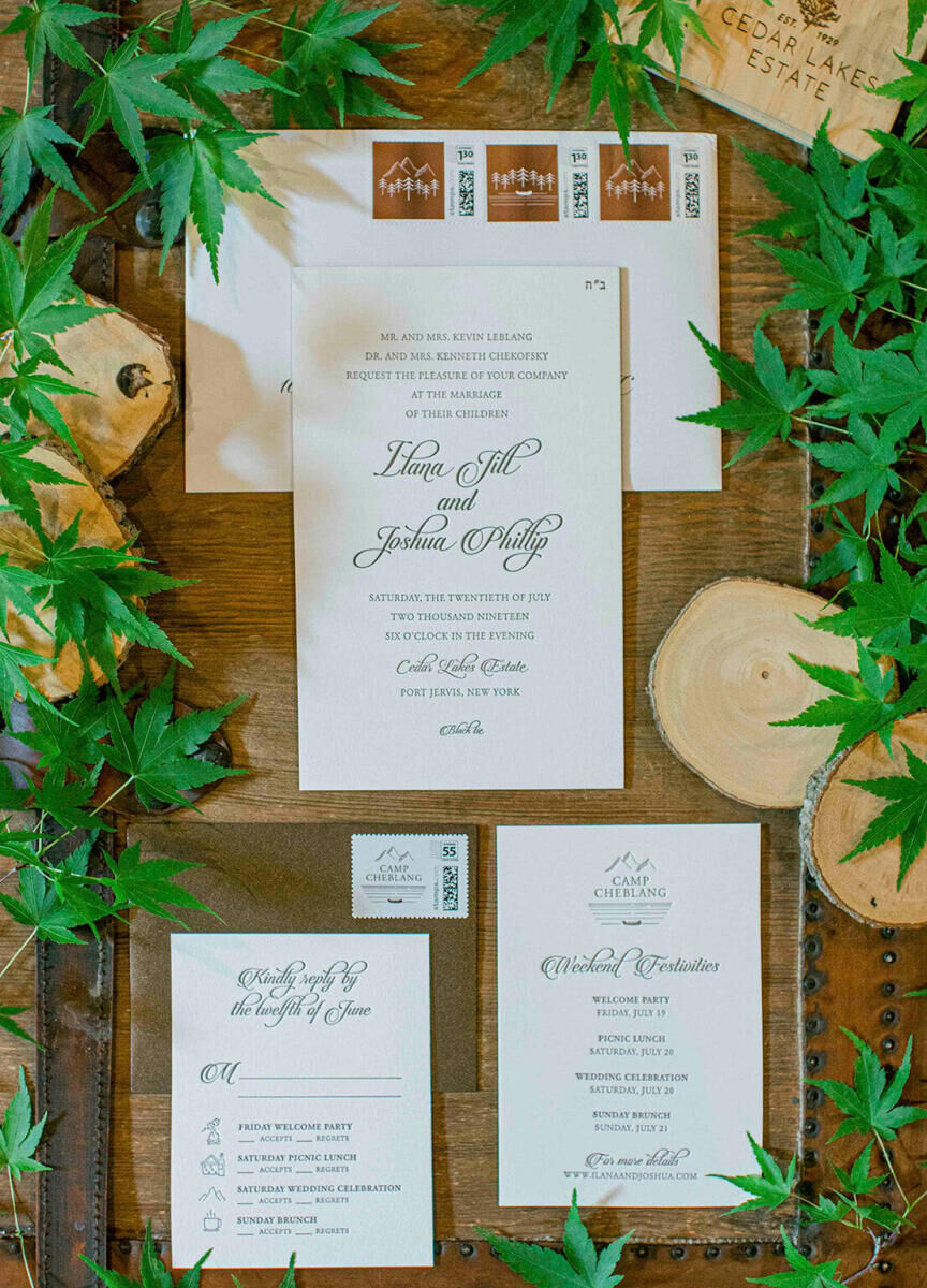 Wedding Tips: An invitation suite flay-lay surrounded by greenery.
