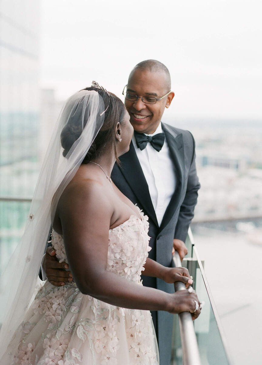 Wedding Tips. A bride and groom smiling at one another as they stand on an outdoor balcony.