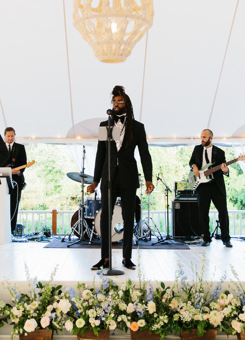 Wedding Tips: A wedding band performing with flowers lining the stage in front of them.