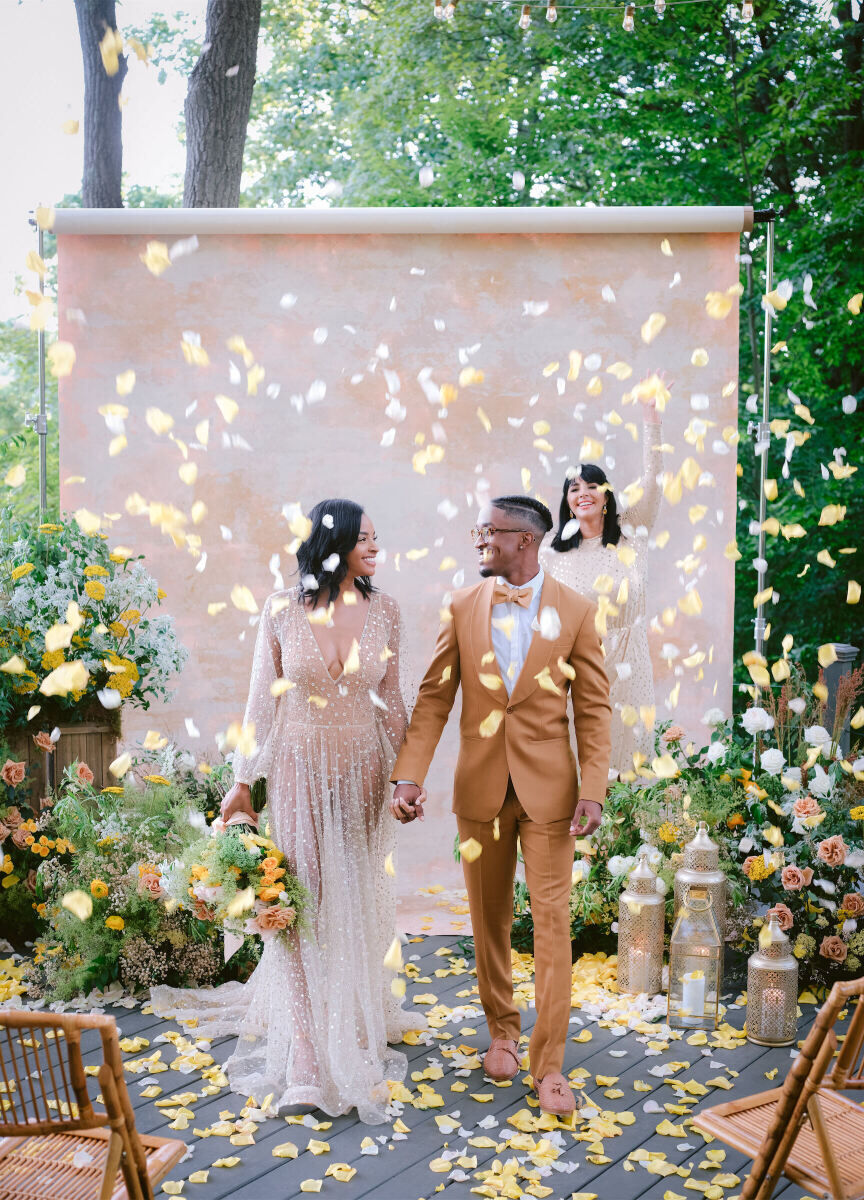 Wedding Tips: A newlywed couple surrounded by confetti, smiling and walking back down the aisle together.