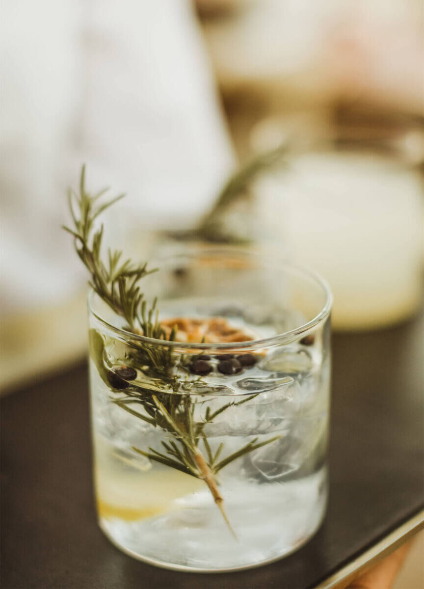 Wedding Tips: A clear cocktail over ice in a rocks glass with a sprig of rosemary as a garnish.