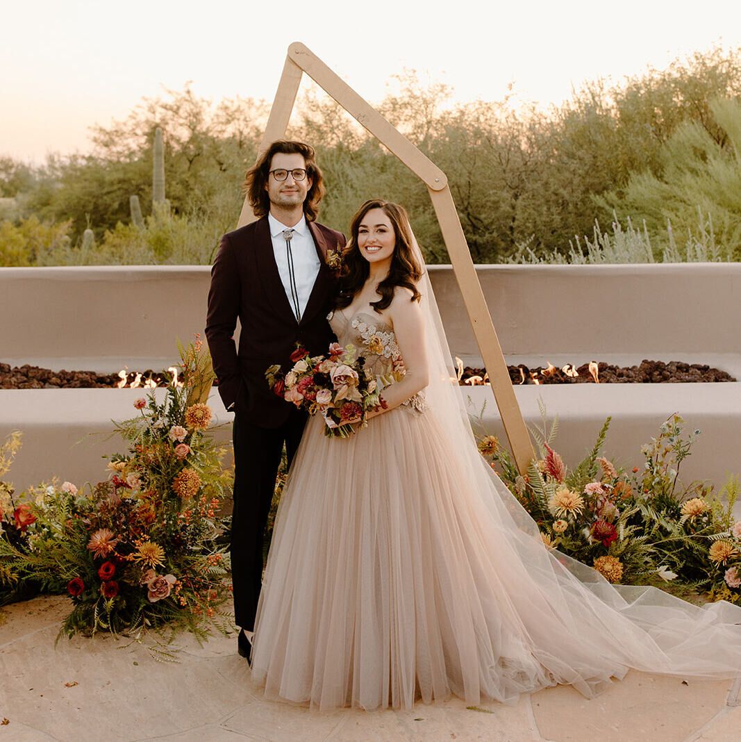 Wedding vendor: Wedding couple, Hannah and Tim standing in front of desert wedding ceremony arch