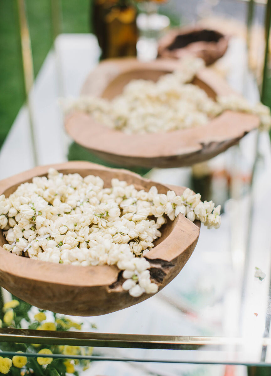 Wedding Website Examples: White florals in wooden bowls at a wedding reception.
