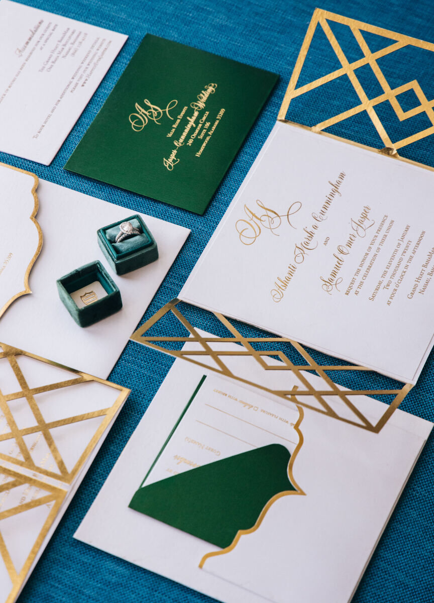 Wedding Website Examples: A flat lay of teal, green, and gold wedding stationery and wedding rings.