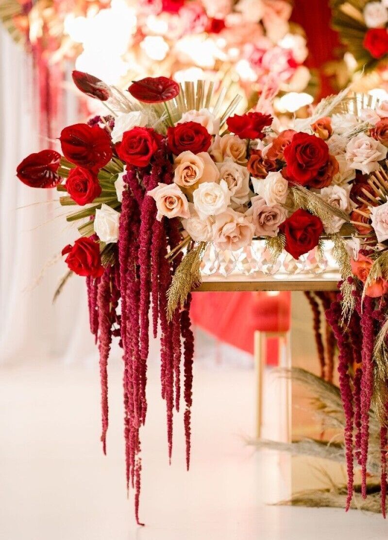 Wedding Website Examples: An elaborate cream, red, and blush floral arrangement hanging over a table at a wedding.