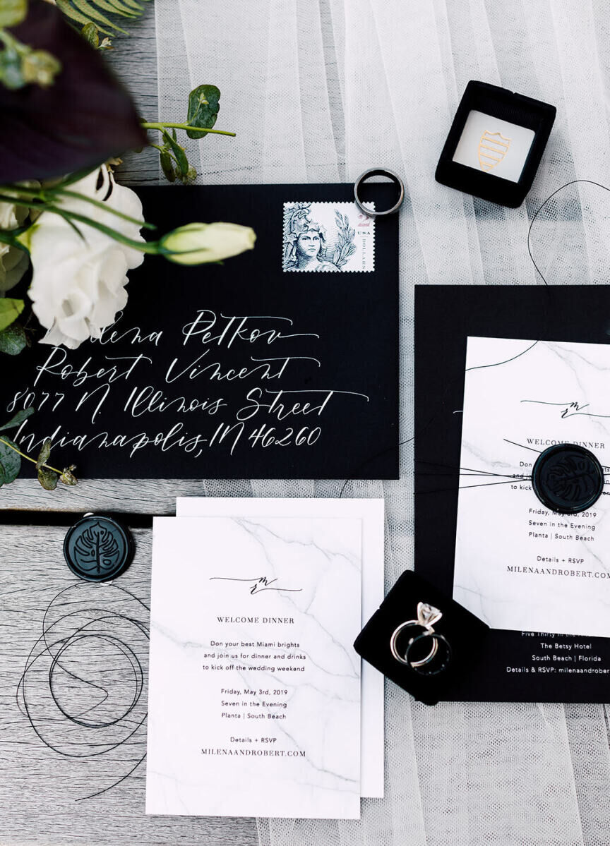 Wedding Website Examples: A flat lay of black and white invitations, stationery, and wedding rings.