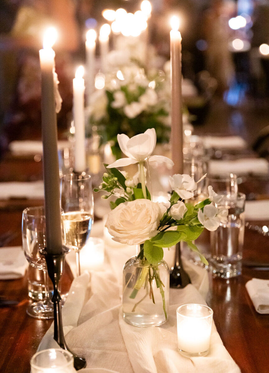 Wedding Website Examples: A tablescape with long-stemmed candles and small white floral arrangements.