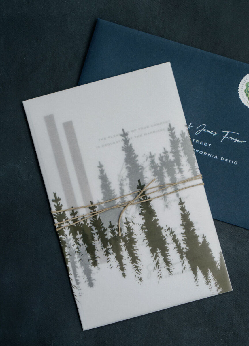 Wedding Website Examples: A flat lay of a navy wedding invitation envelope and white wedding invitation with greenery accents.