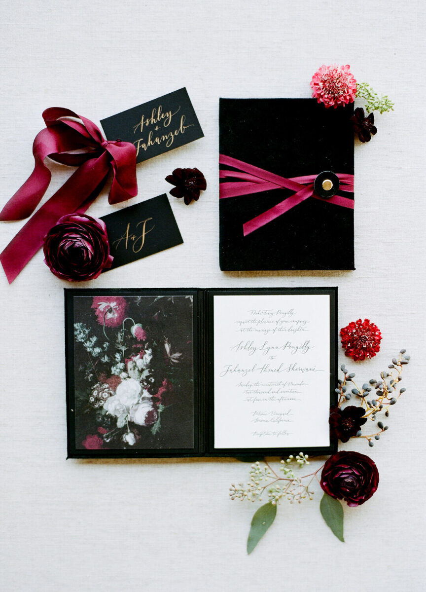 Wedding Website Examples: A flat lay of black and red wedding florals and stationery.