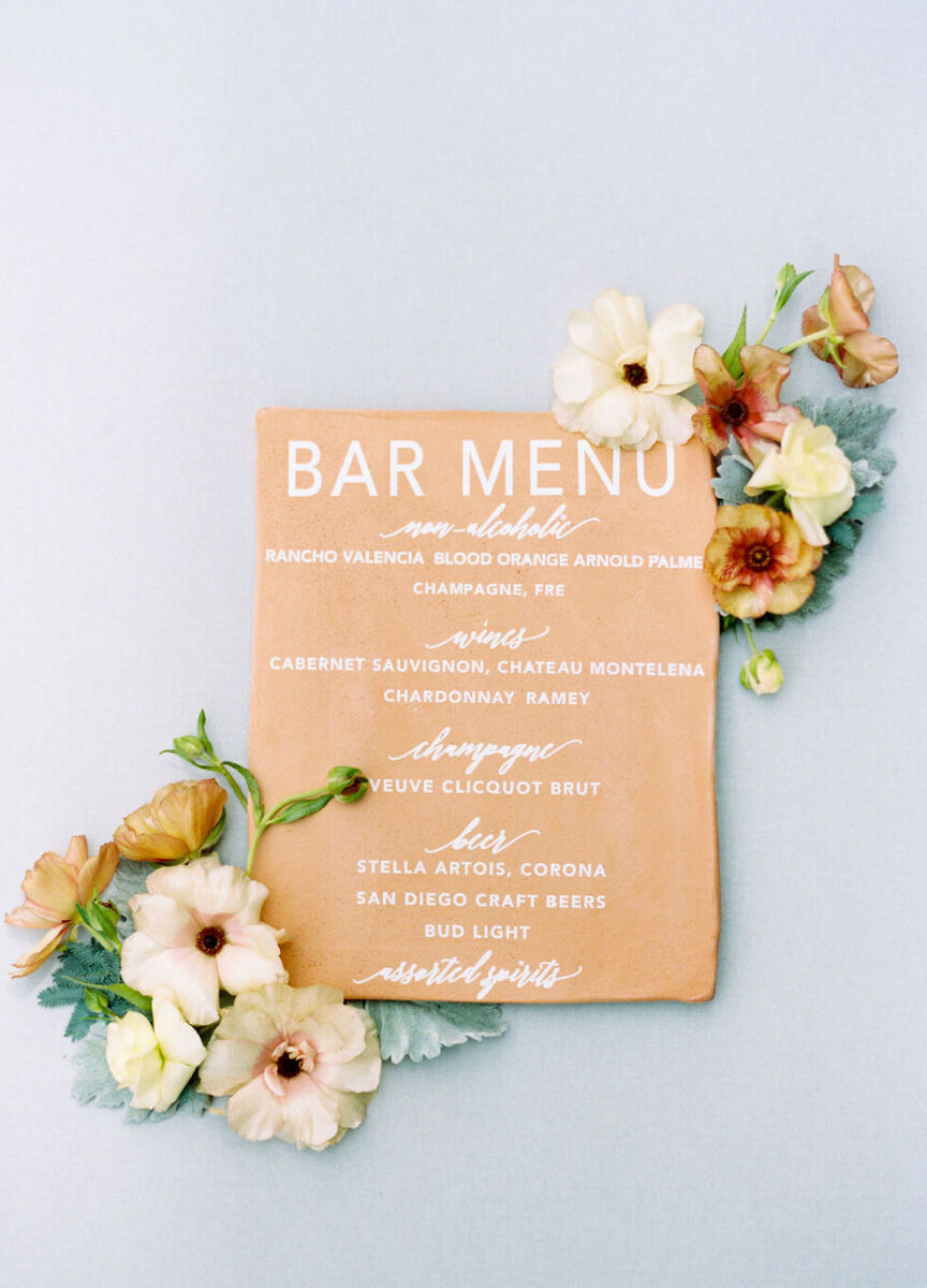 Wedding Website Examples: A peach-colored flat lay of bar menu with florals.