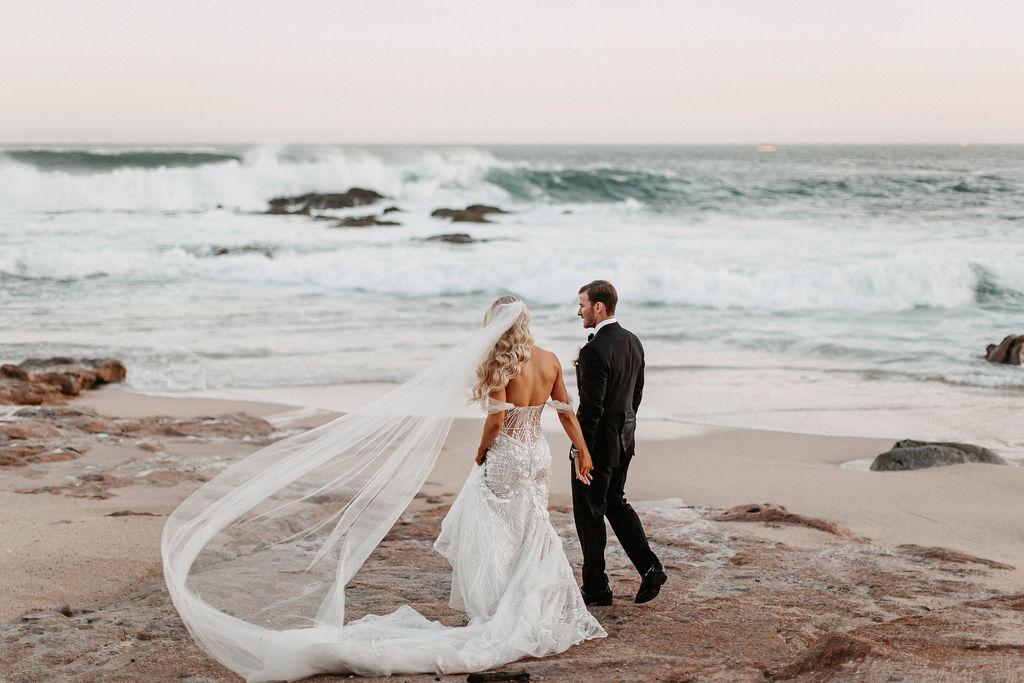 A couple walks in the sand after their wedding at Esperanza