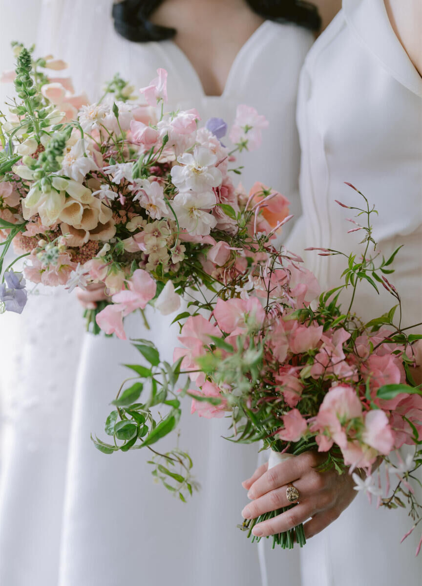 Brides hold complementary bouquets at their whimsical wedding in New Orleans.