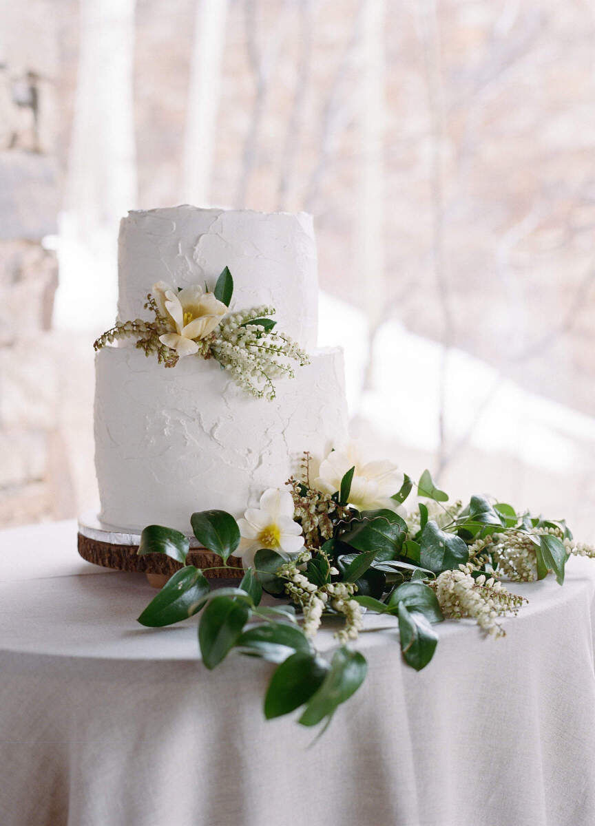 Winter wedding details: White wedding cake adorned with greenery.