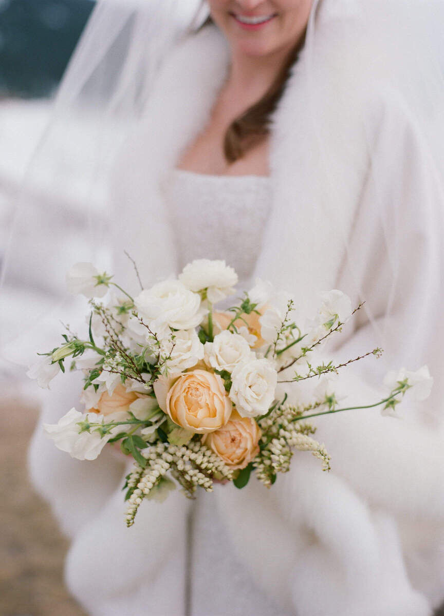 Winter wedding details: A bride holding her white and peach bouquet.