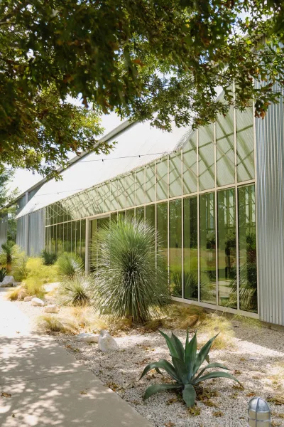 Greenhouse venue exterior featuring an industrial greenhouse facade, edged by agave plants along the frontage.