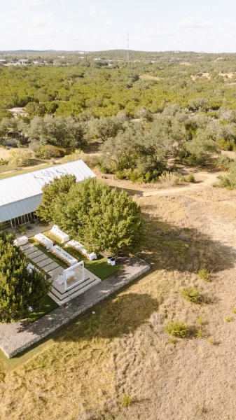 Outdoor reception setup with garden reception decor under a white pergola frame, overlooking rolling hills and an open field.