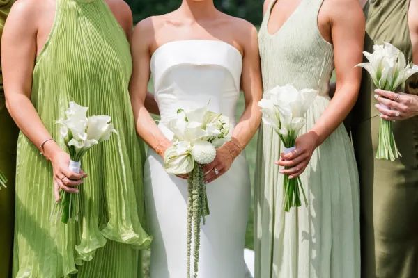 Bridal party bouquets, white calla lily bouquets held by bridesmaids in green dresses, arranged in a clean, modern style.