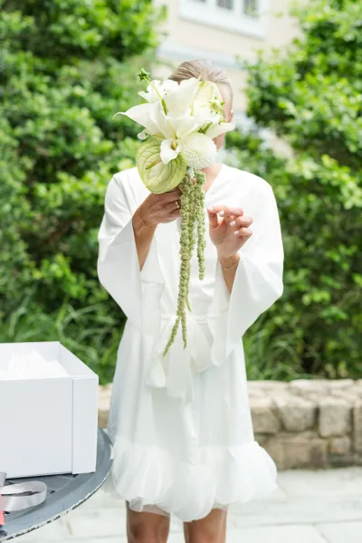 Bridal bouquet, a white and green bouquet featuring calla lilies with sculptural lines, set against garden greenery and a stone wall.