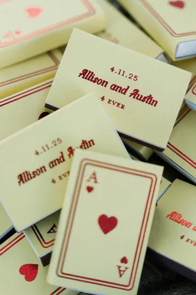Wedding favors featuring personalized matchboxes wedding with playing card design, red heart graphics, and printed names/date on stacked boxes