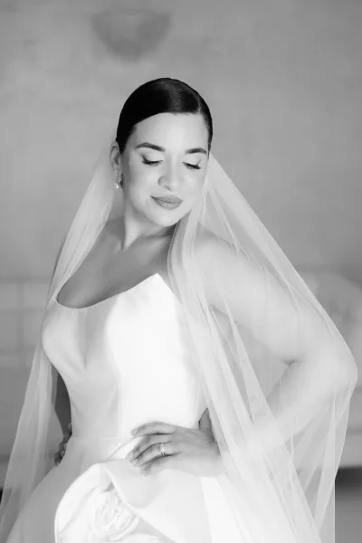 Bridal portrait, a black and white bride photo showing her looking down, wearing a satin gown with a straight neckline and sleek low bun.