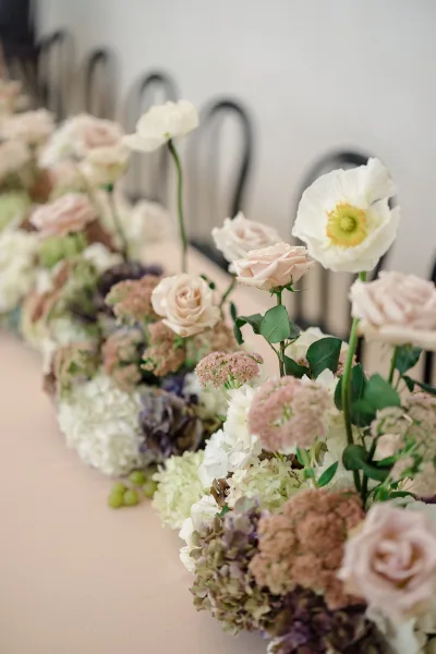 Wedding table garland floral table runner with blush roses, hydrangeas, poppies and eucalyptus greenery on linen at a banquet table