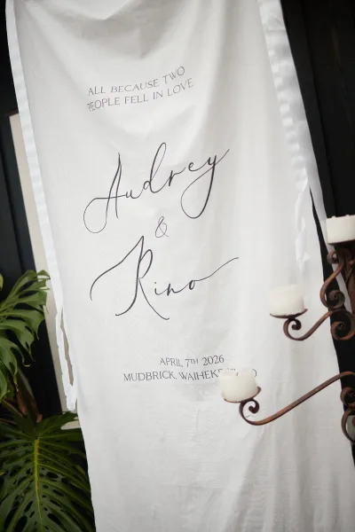Wedding sign as a fabric wedding banner with elegant script, styled beside a candelabra against a black wall.