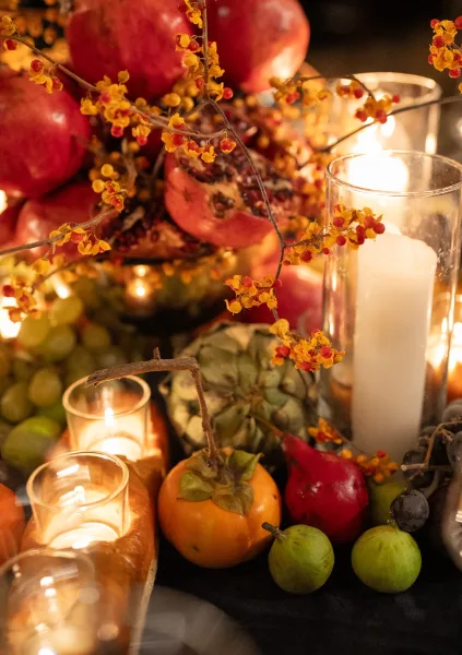 Wedding centerpiece styled as a fall fruit centerpiece with pomegranates arranged low across the tabletop with dark linen.