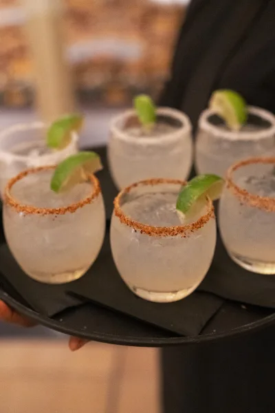Wedding cocktails for cocktail hour drinks, salt-rimmed and glistening in clear glasses, arranged neatly in a minimalist presentation.