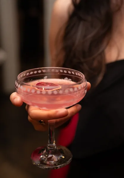 Wedding cocktail, a signature wedding drink garnished with a vivid blood orange slice, shown in a simple, modern presentation.