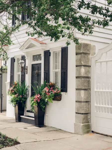 Front door planters arranged as entryway flower pots, set in tall black planters against a crisp white facade.