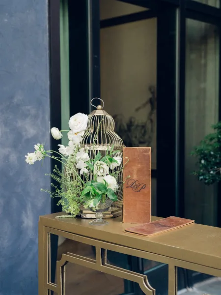 Welcome table decor for a wedding entry table featuring a birdcage, set against a glass window with a black metal frame.