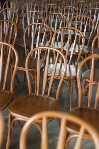 Ceremony seating with wedding ceremony chairs in neat rows, featuring wood chairs with cushions arranged on an indoor floor