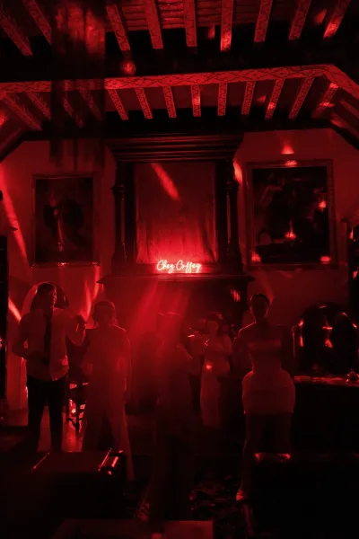 Red lighting and a neon surname sign illuminate the reception dance floor as guests dance together late into the night.