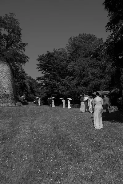 Paper parasols accompany the wedding processional as bridesmaids in floral-print gowns and groomsmen in suits cross a grassy lawn