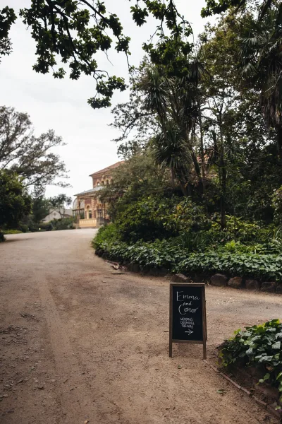 Wedding signage chalkboard wedding sign on a wooden A-frame with an arrow, set along a gravel garden path near a historic building