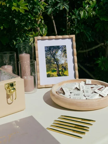 Wedding guest book alternative guest book card station with gold pens, framed photo and blush candles on a foliage-lined tabletop display