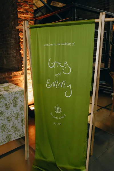 Wedding welcome sign on a fabric wedding banner with a disco ball graphic, set against a brick wall and metal staircase backdrop.