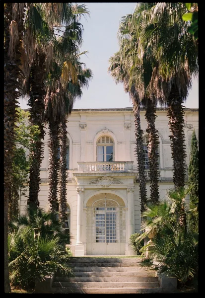 Wedding venue exterior showcasing a stately villa facade centered on an arched doorway, with a symmetrical design fit for a romantic estate.
