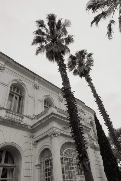 Venue exterior of a mansion wedding venue with arched windows set in a grand stucco facade, featuring symmetrical lines and stately scale.