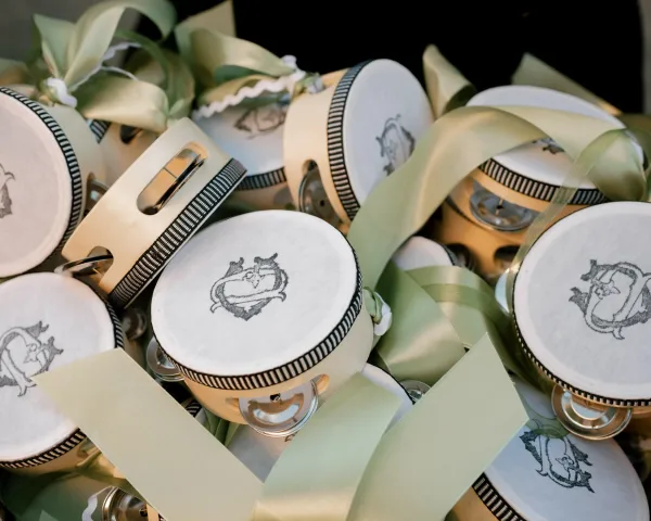 Wedding favors with personalized wedding favors details, ribbon-wrapped round boxes with monogram labels, tags and jingle bells on dark backdrop