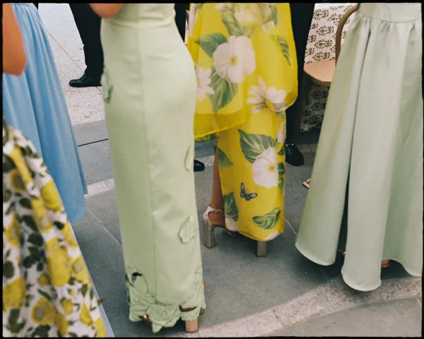 Wedding guest outfits featuring floral wedding guest dress styles in pastel prints, shown with block heel sandals on a stone walkway outdoors