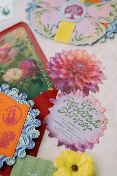 Wedding invitation suite with die cut wedding invitation cards, scalloped edges, floral illustrations, and wax seal on light fabric surface