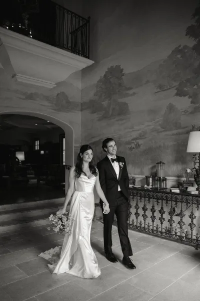 Wedding couple portrait of bride and groom holding hands on an indoor staircase, her bouquet and train beside a wrought iron railing