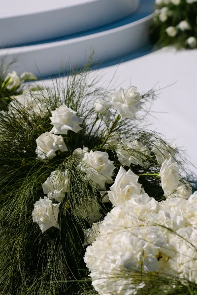 Ceremony flowers arranged low along clean white steps, featuring white hydrangeas for soft volume across the bright white floor.