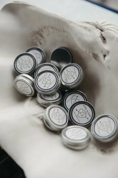 Wedding favor tins arranged as sea salt wedding favors, each filled and sealed, set neatly on a white tabletop.