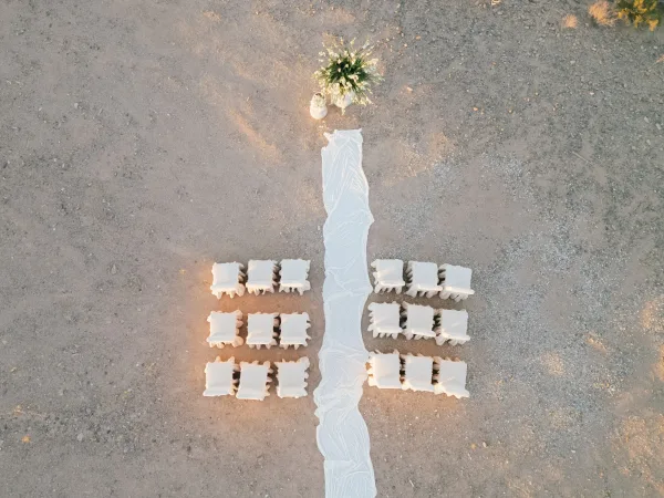 Ceremony setup showcasing a clean ceremony seating layout with a floral arrangement on desert ground of dirt and gravel.