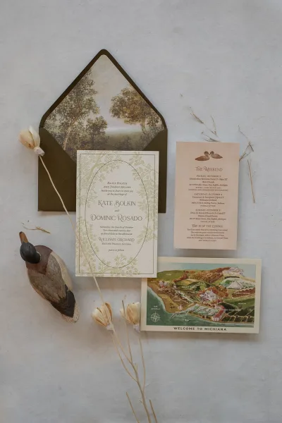 Invitation suite wedding invitation flat lay with illustrated envelope liner, itinerary and map cards, dried flowers on light fabric backdrop