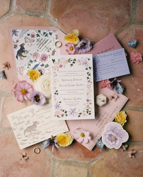 Wedding invitation suite featuring floral wedding invitations laid out on terracotta tile, styled with a small ring box.