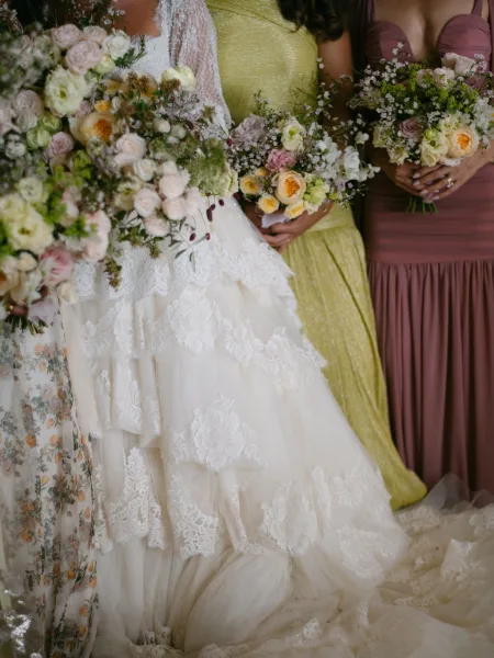 Bridesmaid bouquets of garden rose bridesmaid bouquets with blush, cream, and yellow roses, baby’s breath, and greenery against a neutral indoor backdrop